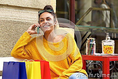 Female shopper sitting outdoors and using mobile phone Stock Photo