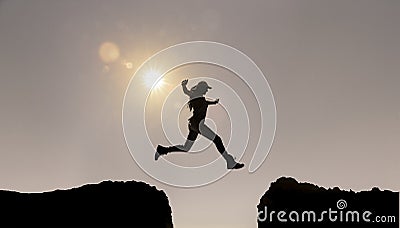 Female Silhouette Jumping over canyon Stock Photo