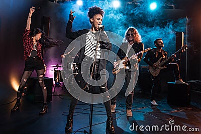 Female singer with microphone and rock and roll band performing hard rock music Stock Photo
