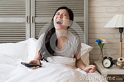 Female sitting in the bed and burst into laughter Stock Photo