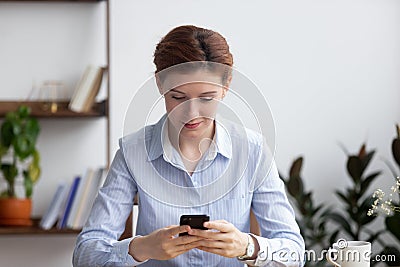 Female sitting in office room holding smartphone reading message Stock Photo