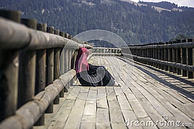 Female sitting on wooden path in nature Stock Photo