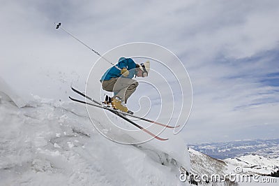 Female Skier Jumping Off Icy Overhang Stock Photo