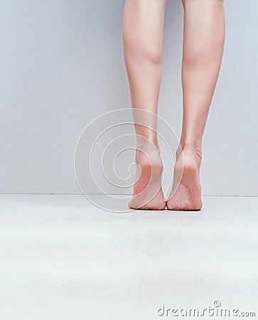 Female slender legs, feet are on the light gray background floor Stock Photo