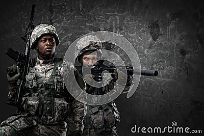 Female soldier aiming rifle near her black comrade Stock Photo