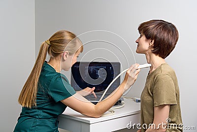 Female sonographer examing throat. Medical worker doing ultrasound diagnostics Stock Photo