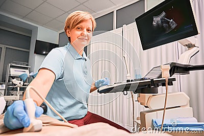 Charming female doctor doing ultrasound examination in clinic. Stock Photo