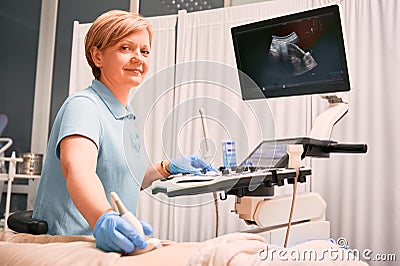 Charming female doctor doing ultrasound examination in clinic. Stock Photo