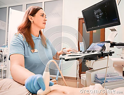 Doctor performing ultrasound procedure in modern clinic. Stock Photo