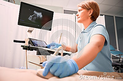 Doctor performing ultrasound procedure in modern clinic. Stock Photo