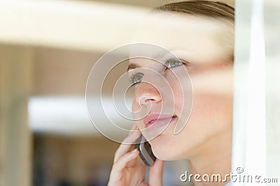 Female speaking over the cellphone , view through a glass. Young woman having a conversation over the cellphone , view Stock Photo