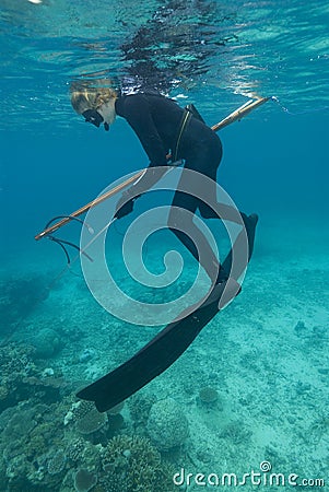 Female spear-fisher reloads gun above coral reef Stock Photo