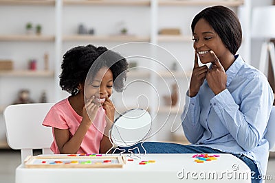 Female speech pathologist exercising with little girl with language difficulties Stock Photo