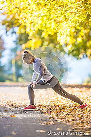 Female sporty young woman doing stretching or warming the body and preparing to jogging Stock Photo