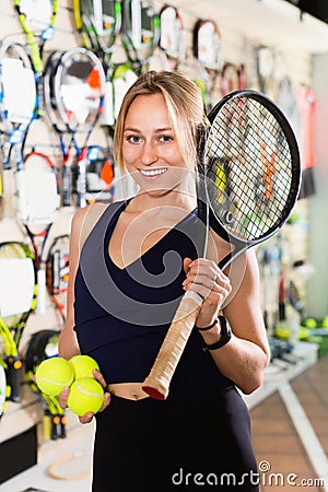 Female standing in sporting goods store with balls and racket Stock Photo