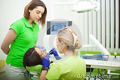 Female stomatologist in protective gloves examining patient`s teeth. Dentist caries treatment at dental clinic office Stock Photo