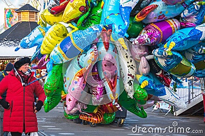 Female street vendor sells helium balloons at Christmas funfair Hyde Park Winter Wonderland in London Editorial Stock Photo