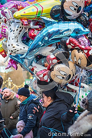 Female street vendor sells multiple cartoon character helium balloons Editorial Stock Photo