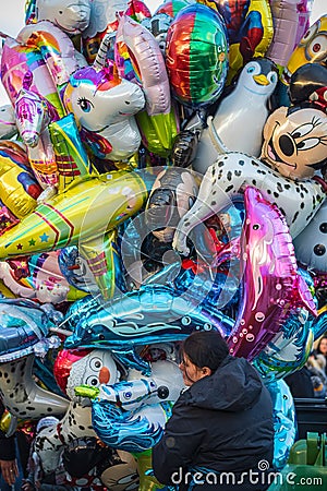 Female street vendor sells multiple cartoon character helium balloons Editorial Stock Photo