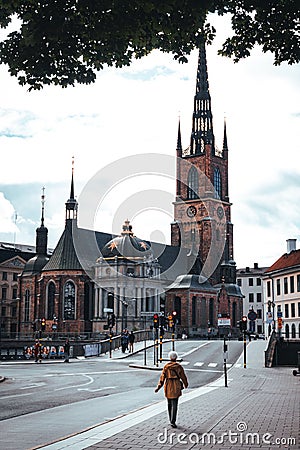 Female strolls along a cobblestone street in front of the Riddarholmen Church in Stockholm, Sweden Editorial Stock Photo