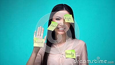 Female student covered with English body parts sticky notes, learning language Stock Photo