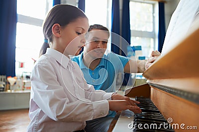 Female Student Enjoying Piano Lesson With Teacher Stock Photo