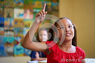 Female Student Raising Hand During Test In Class At School Stock Photo