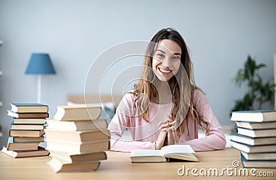 Female student sits at a table with books preparing for exams Stock Photo