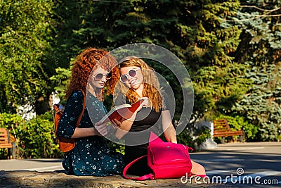 Female students read a book in park. Stock Photo