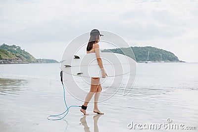 female surfer in bikini holding surfboard and going Stock Photo