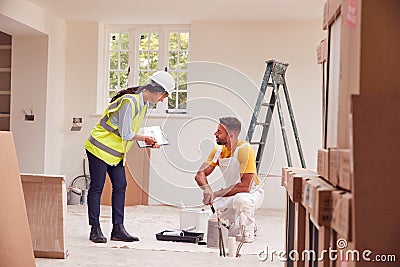 Female Surveyor With Clipboard Meeting With Decorator Working Inside Property Stock Photo