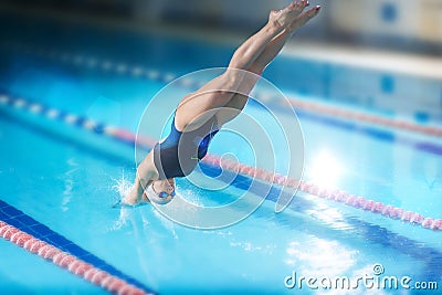 Female swimmer, that jumping into indoor swimming pool. Stock Photo