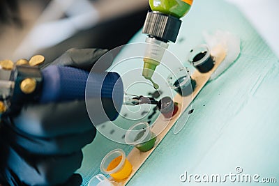 Female tattooist loading the tattoo machine with ink. Stock Photo