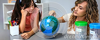 Female teacher giving ecology lesson with handmade globe world to girl student Stock Photo