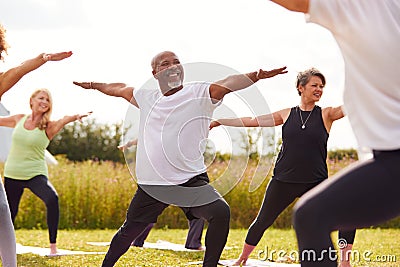 Female Teacher Leading Group Of Mature Men And Women In Class At Outdoor Yoga Retreat Stock Photo