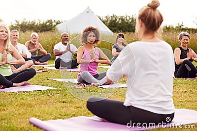 Female Teacher Leading Group Of Mature Men And Women In Class At Outdoor Yoga Retreat Stock Photo