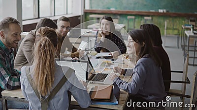 Female team leader brings documents to creative business team. Mixed race group of people meeting in modern office. Stock Photo