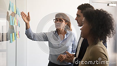 Female team leader explain project to colleagues with sticky notes Stock Photo