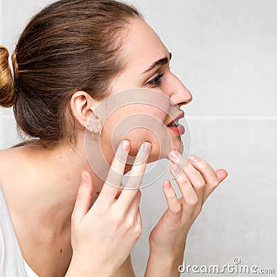 Female teenager with acne checking her zits, pimples or blemishes Stock Photo