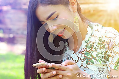 Female teenager so cute using smartphone happily in park Stock Photo