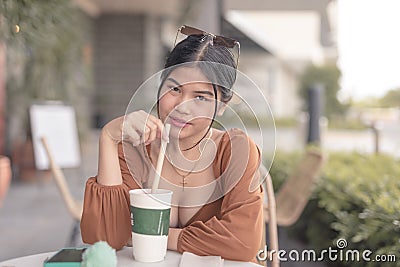 A female teenager poses for the camera with a smized eyes while holding the straw of her frappe Stock Photo