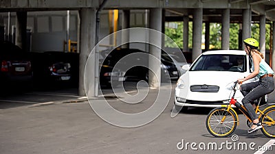 Female teenager riding bicycle on road front of driving car, traffic collision Stock Photo