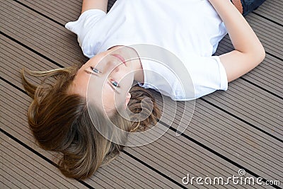 Female teenager smiling, layingon the floor. Summer, portrait of young girl with long, blonde hair Stock Photo