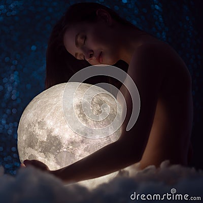 Female tenderness, a beautiful girl holds the moon against the background of stars and sky, zodiac and astrology, female magic and Stock Photo