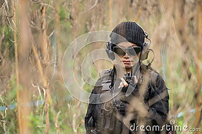 Female Thai soldier communicating with walkie-talkie during field training Stock Photo