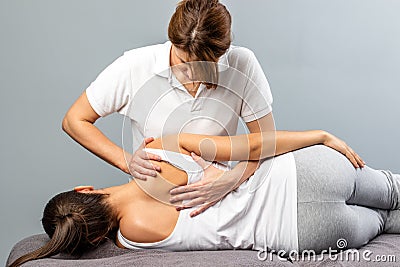 Female therapist manipulating shoulder blade on young female pat Stock Photo