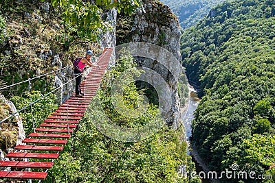 Female tourist on a via ferrata bridge in Vadu Crisului, Padurea Craiului mountains, Romania, with the Crisul Repede defile/gorge Stock Photo