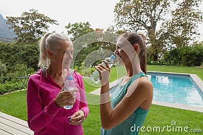 Female trainer and active senior woman drinking water in the backyard Stock Photo