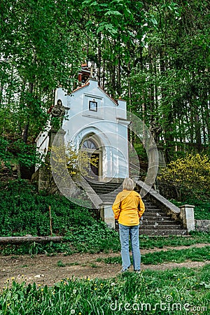 Female traveler looking at small tiny chapel of Our Lady of Lourdes,Broumovsko region,Czech republic.Rural Catholic church in Editorial Stock Photo
