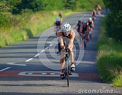 Female Triathlete on road cycling stage of triathlon. Editorial Stock Photo